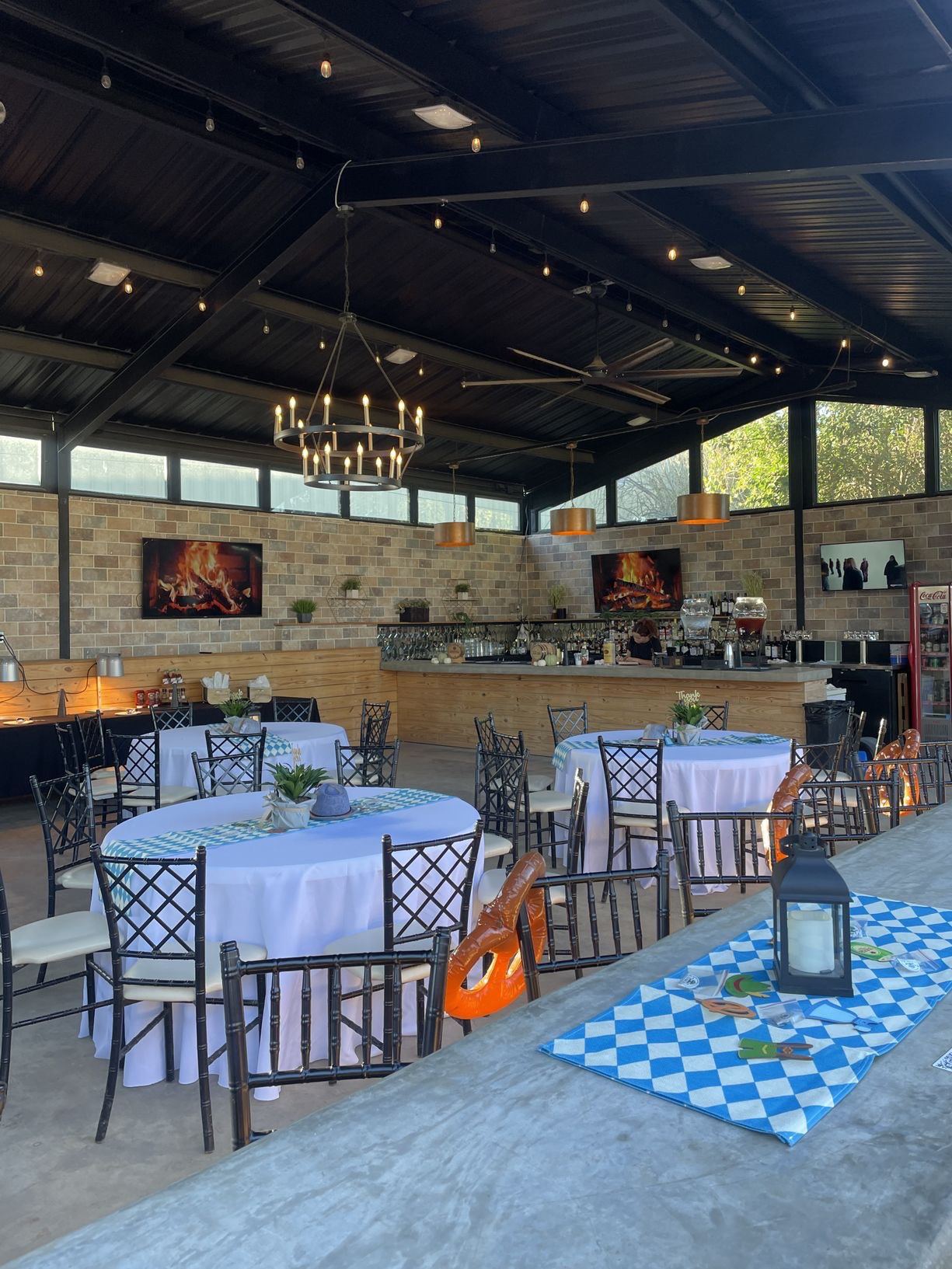 Round tables dressed in white linens under the chandeliers in Screaming Goat's event space